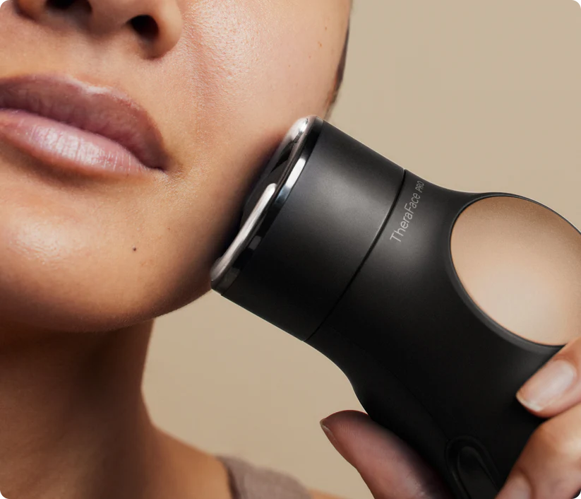 Un dispositivo negro de tratamiento facial se usa en la mejilla de una mujer.