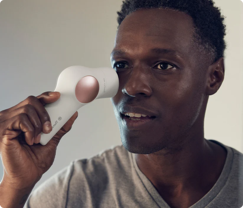 Un hombre usa un dispositivo de cuidado de la piel blanco cerca de su ojo.