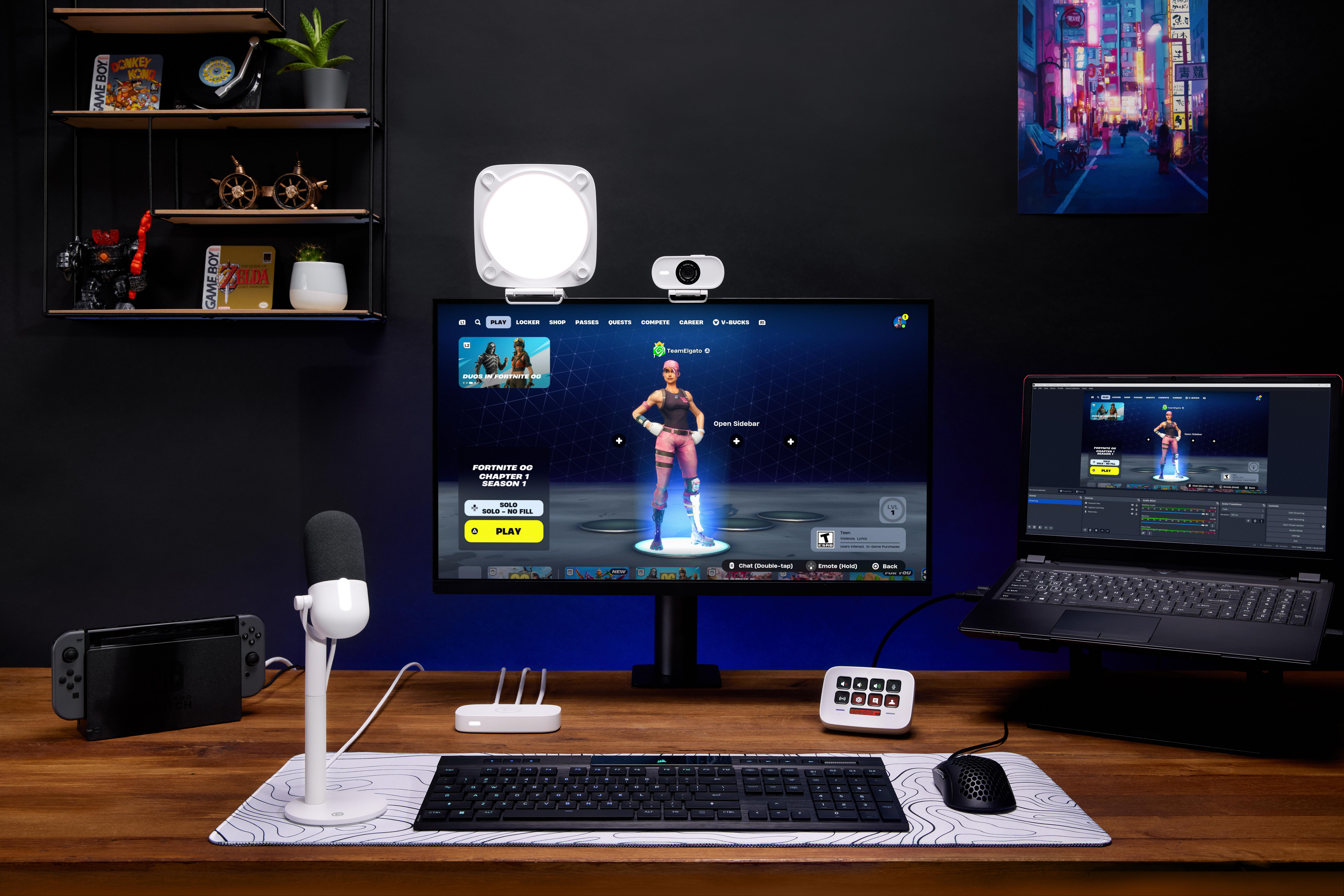 Gaming-Setup mit Monitor, Laptop, Tastatur, Maus, Mikrofon und Nintendo Switch.