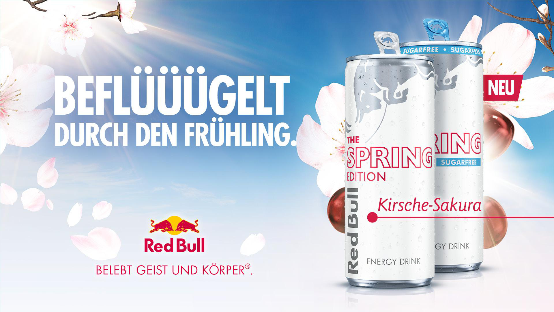 Red Bull Dosen mit Kirsche-Sakura Geschmack, umgeben von Frühlingsblüten.