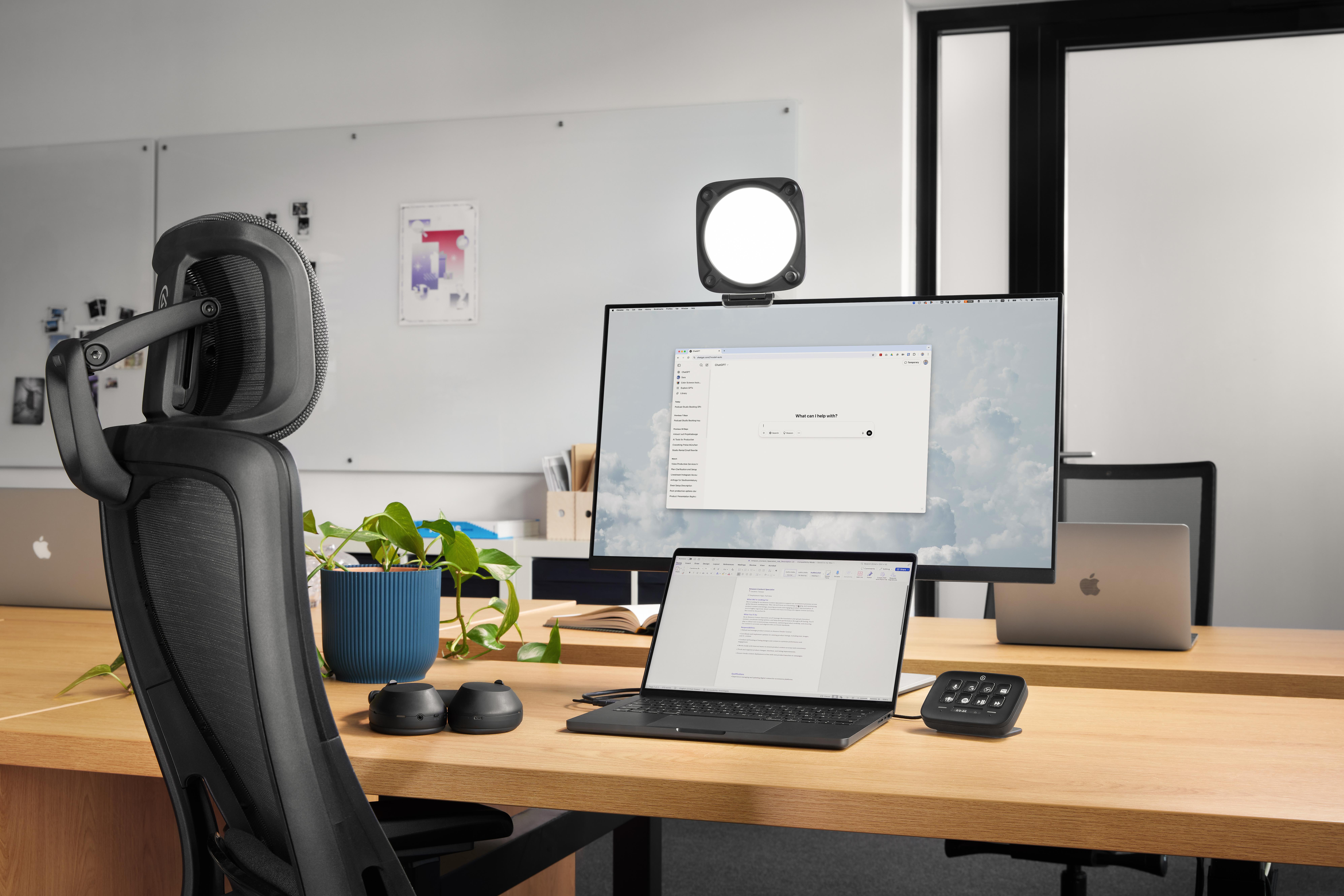 Ein Schreibtisch mit Computern, einem Laptop, Kopfhörern und einer Pflanze.