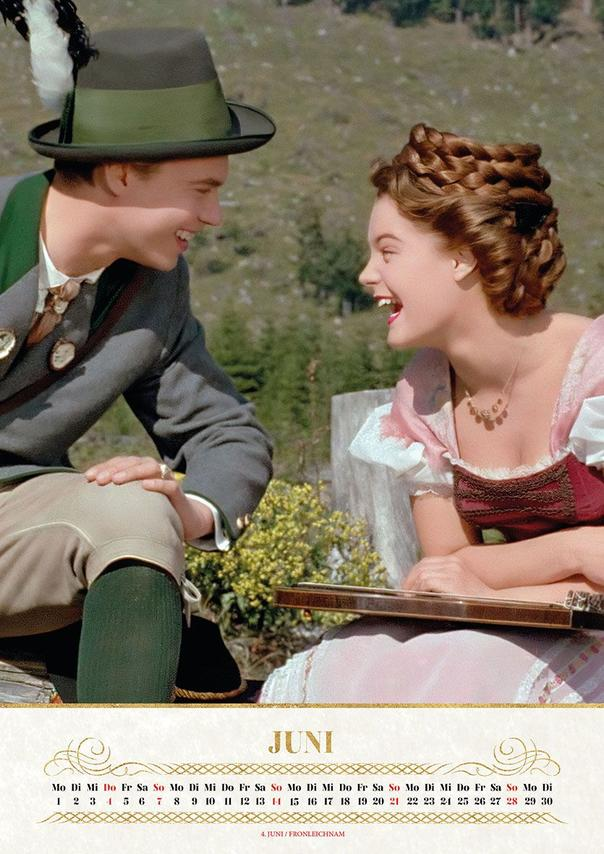Ein Mann mit Hut und eine Frau mit Zopf lachen im Freien.