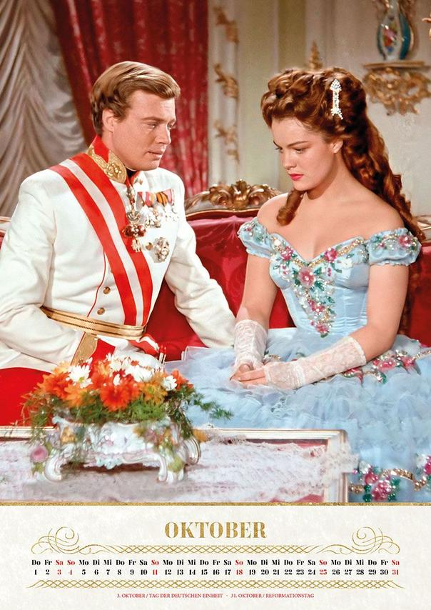 Ein Mann in Uniform und eine Frau in blauem Kleid sitzen nebeneinander.