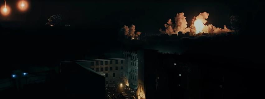 Explosionen erhellen den Nachthimmel über einer Stadt und Gebäuden.
