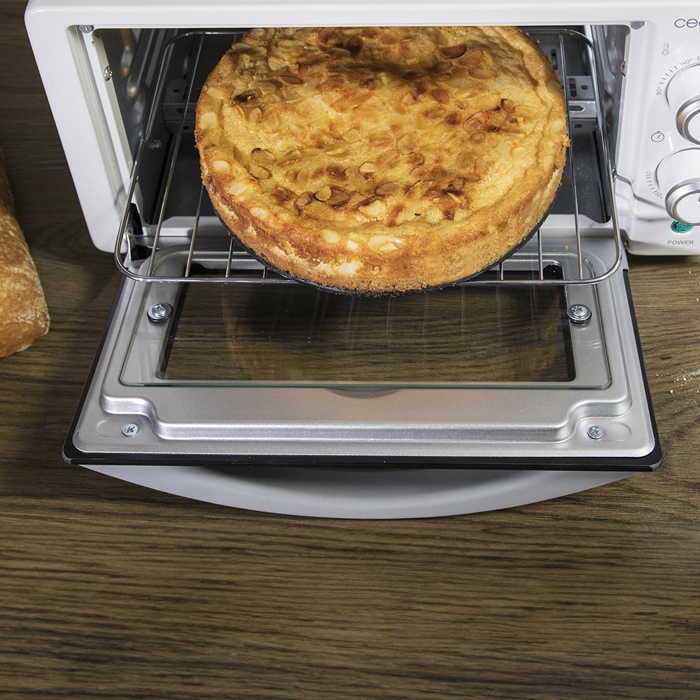 Un pastel dorado con almendras dentro de un mini horno sobre mesa madera.