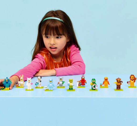 Ein Mädchen spielt mit Lego-Tierfiguren auf einem blauen Tisch.