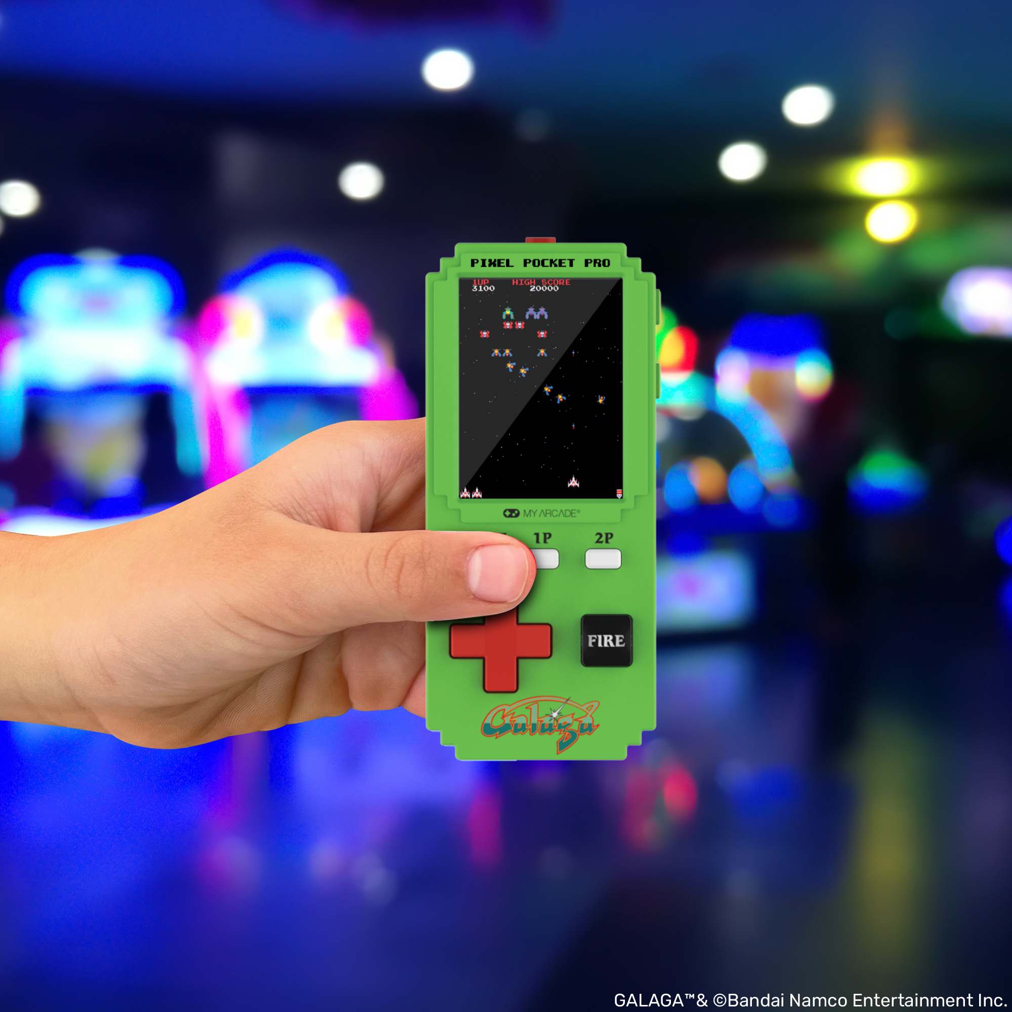 Grünes Handheld-Spielgerät mit Galaga-Spiel im Hintergrund mit Lichtern.