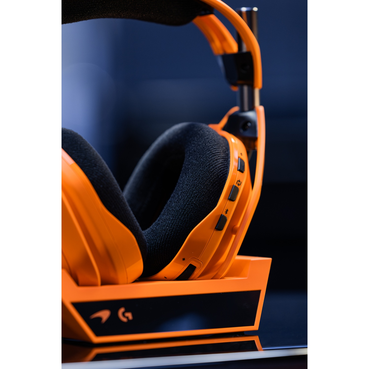 Cuffie da gaming arancioni con padiglioni neri appoggiate su un supporto.
