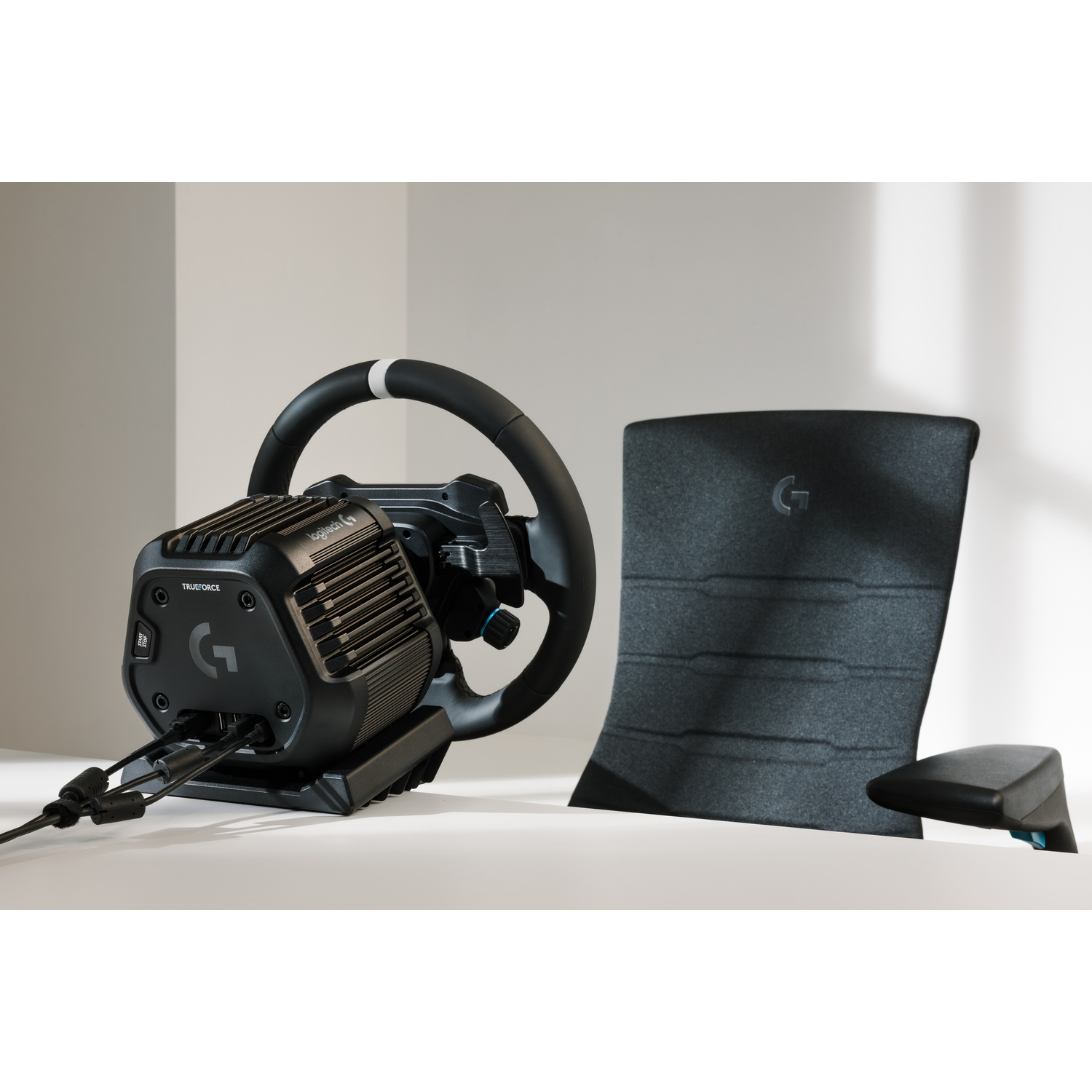 Un volante e set di pedali Logitech G neri su una superficie bianca.