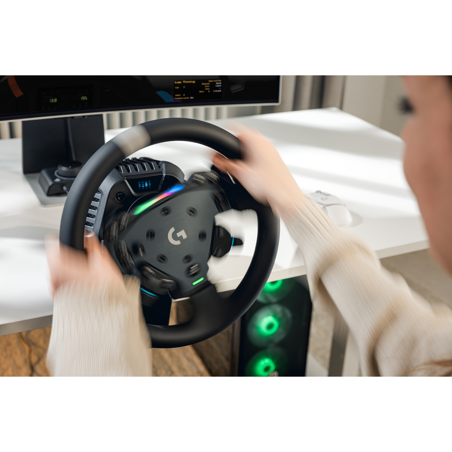 Una persona usa un volante da corsa davanti a un monitor con case PC illuminato.