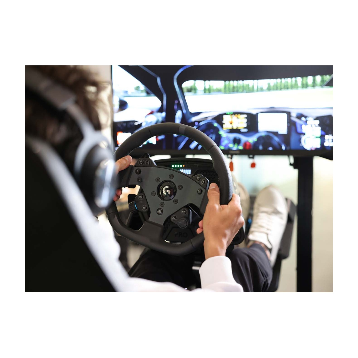 Persona gioca a un gioco di corse con volante, cuffie e pedali.
