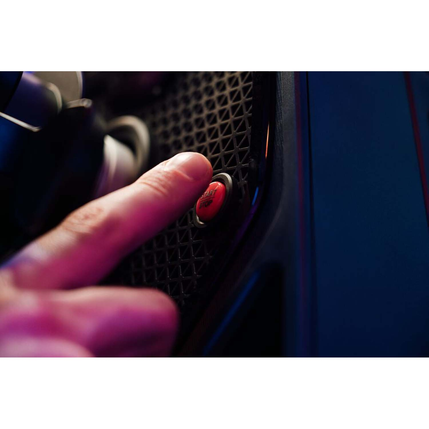 Un dito preme un pulsante rosso start/stop su una griglia nera.