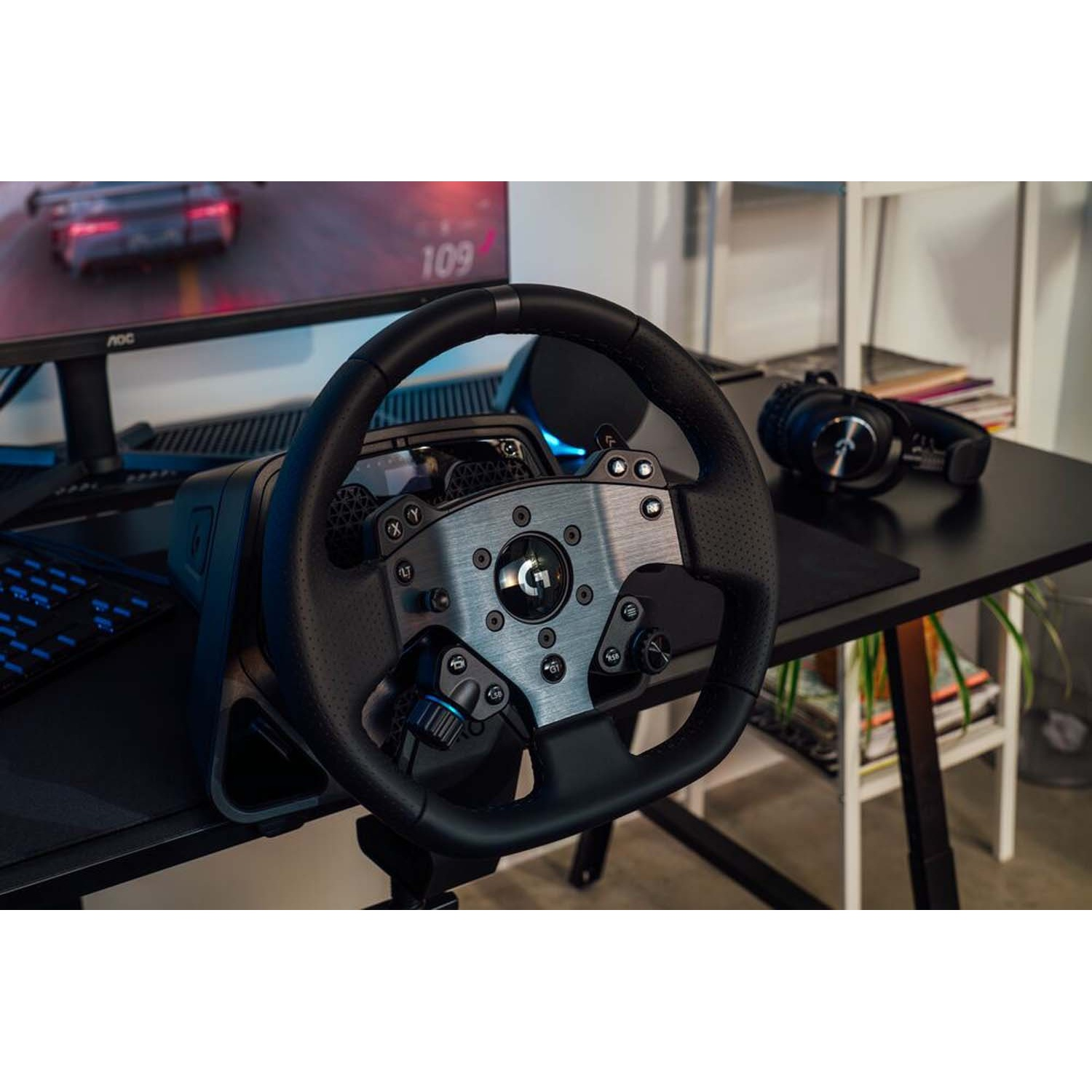 Un volante da gaming su una scrivania, con cuffie e monitor nelle vicinanze.