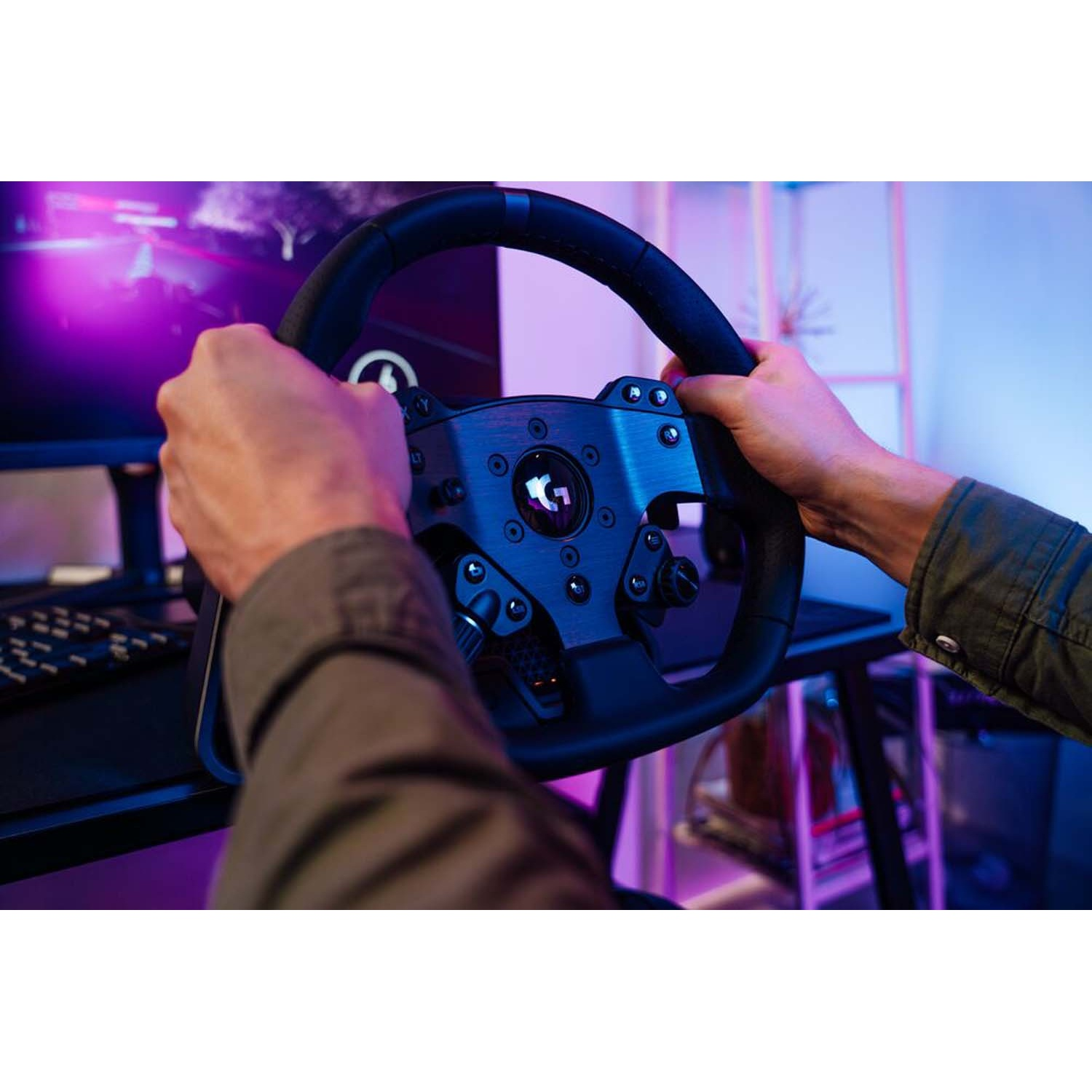 Mani afferrano un volante da corsa con monitor e illuminazione viola sullo sfondo.