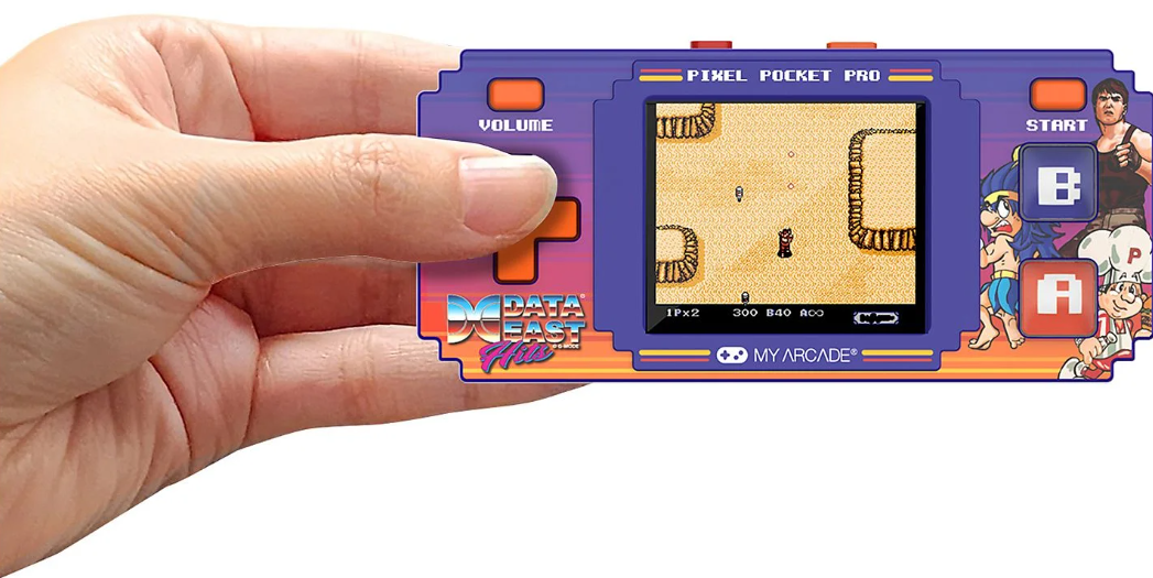 Hand hält ein violettes Handheld-Spielgerät mit Pixel-Art-Spiel und bunten Charakteren.