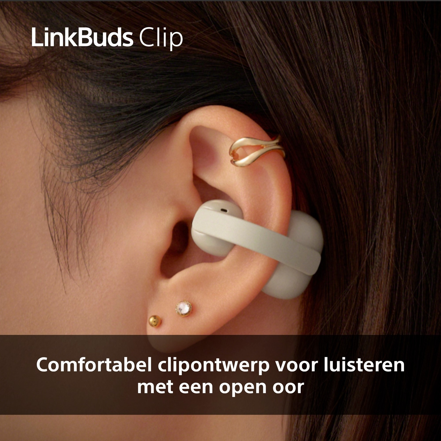 Close-up van een oor met witte oortelefoon en gouden sieraden.