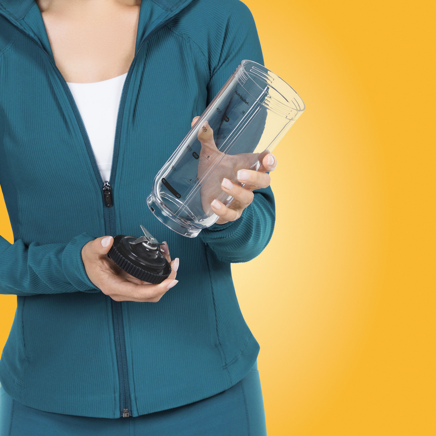 Mujer con ropa deportiva sostiene un vaso transparente y una cuchilla.
