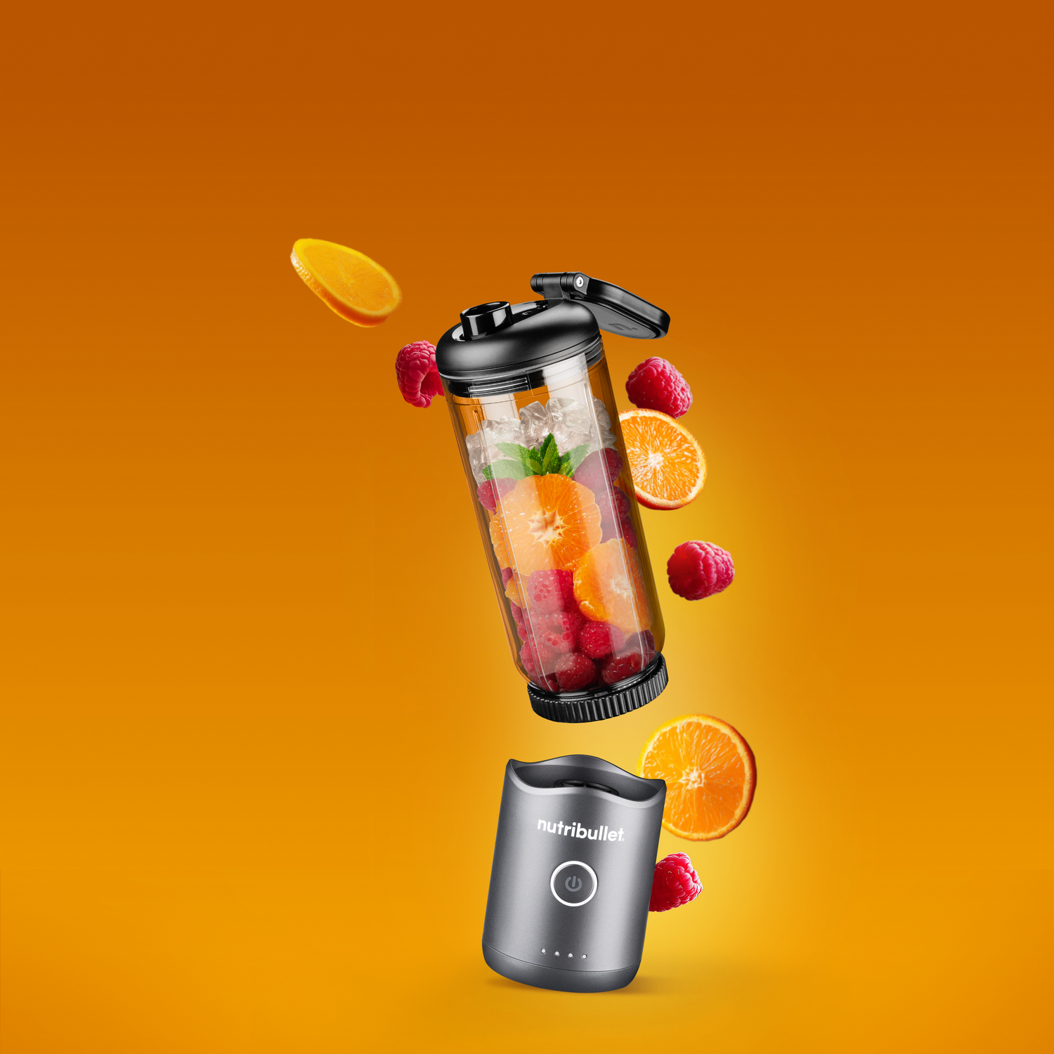 Una licuadora portátil con frutas y hielo flota sobre un fondo naranja.