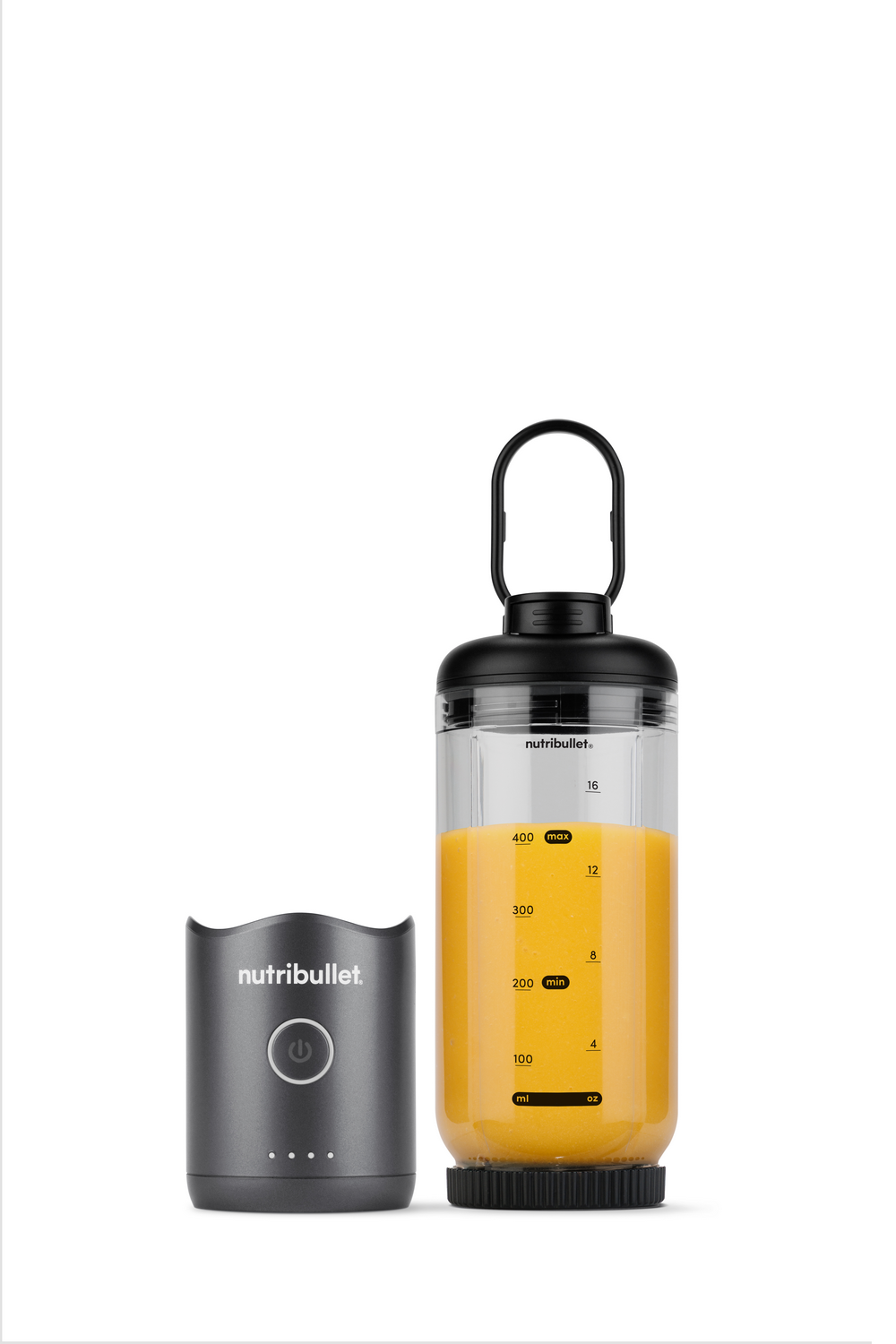 Una base motorizada gris junto a un vaso transparente con zumo de naranja.