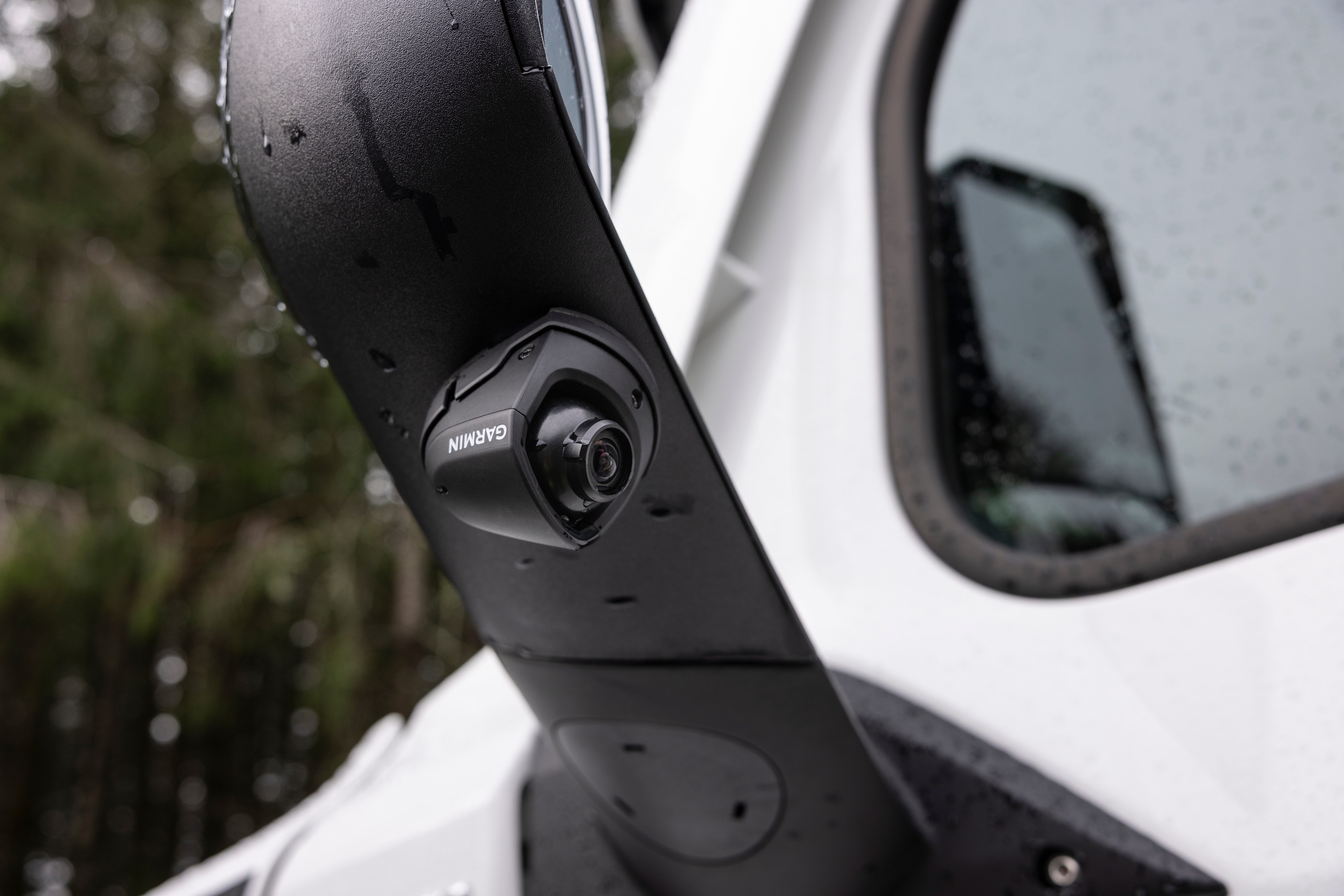 Telecamera Garmin su specchio nero di veicolo bianco con gocce d'acqua.