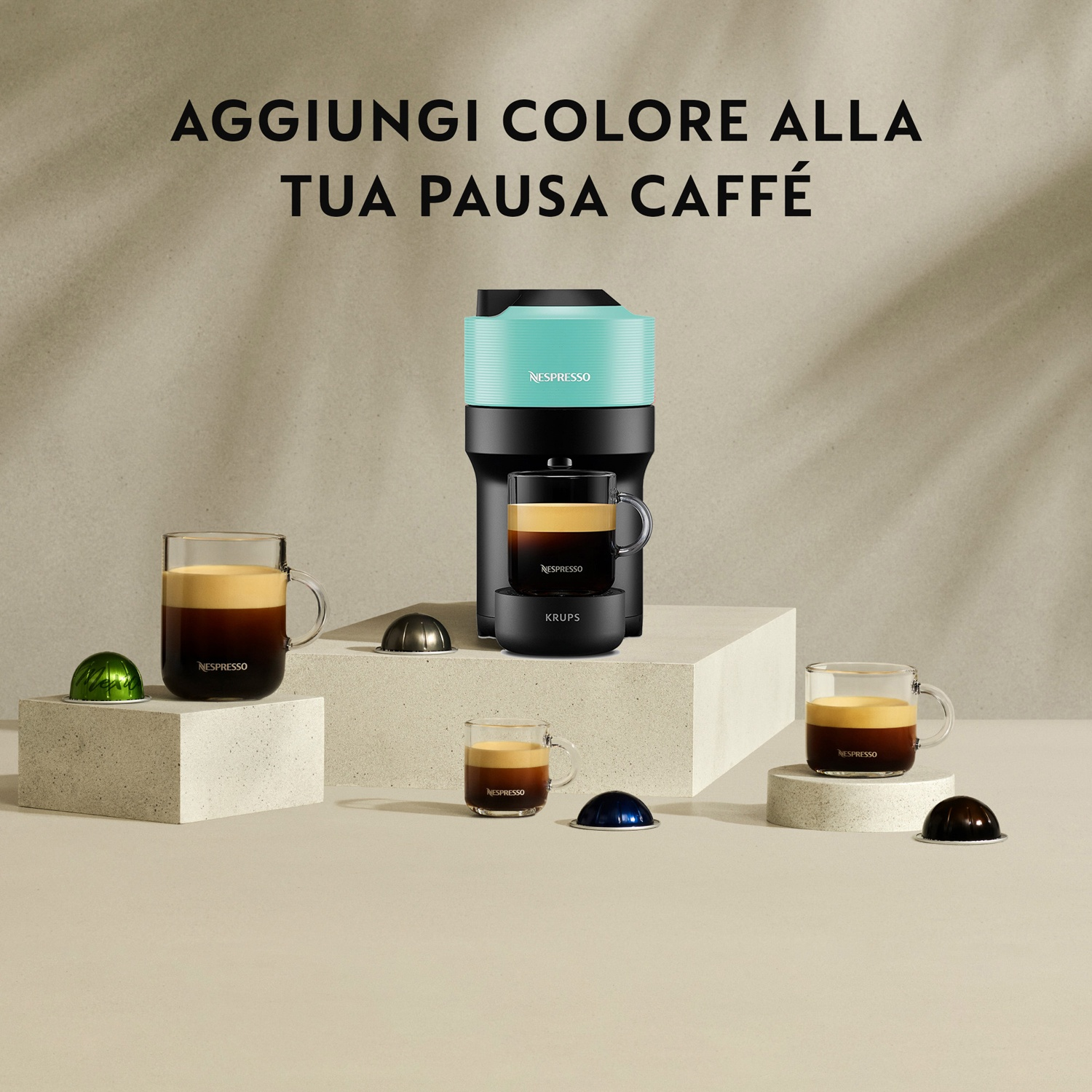 Una macchina da caffè Nespresso turchese con bicchieri e capsule.