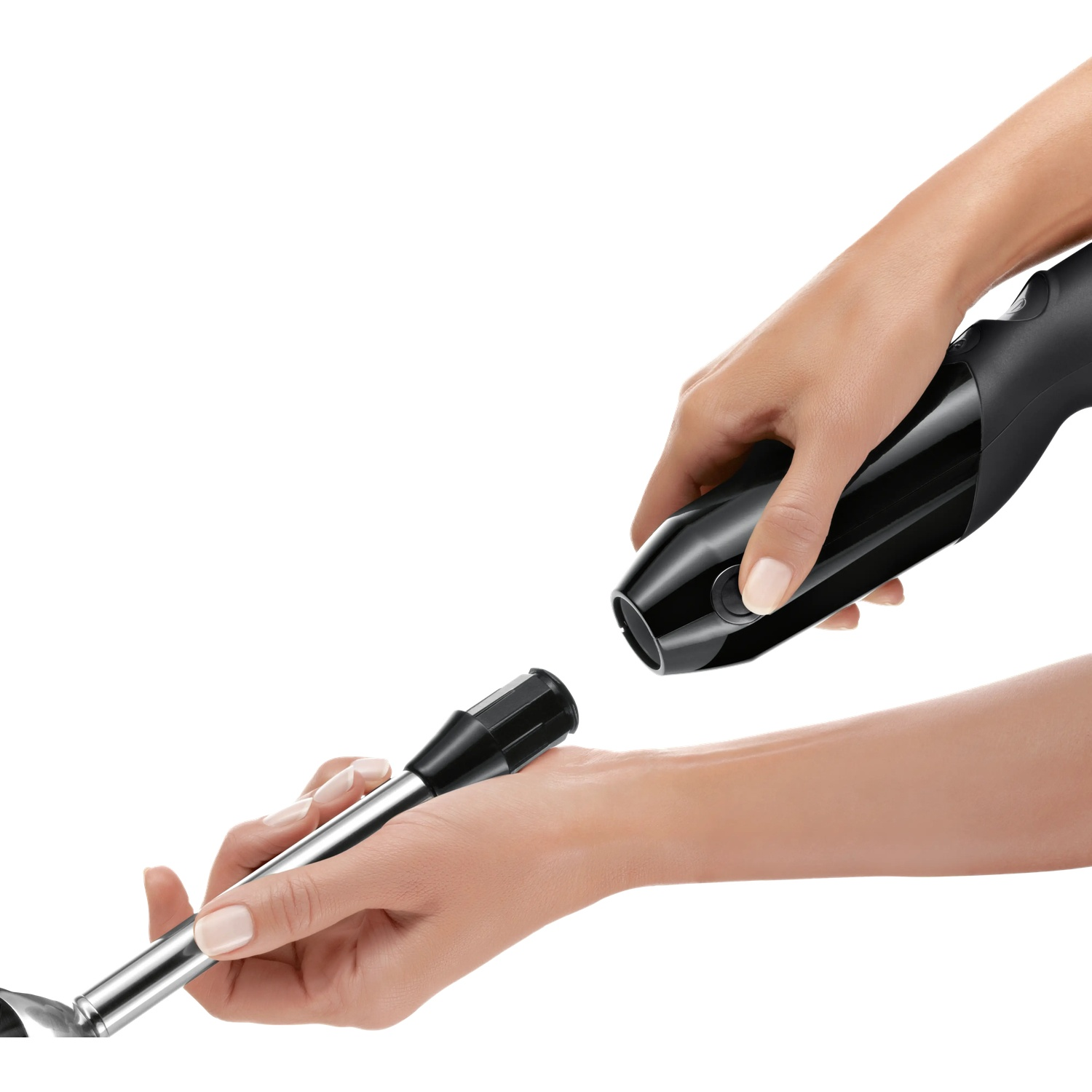A hand holds a black immersion blender and another hand holds the metal attachment.
