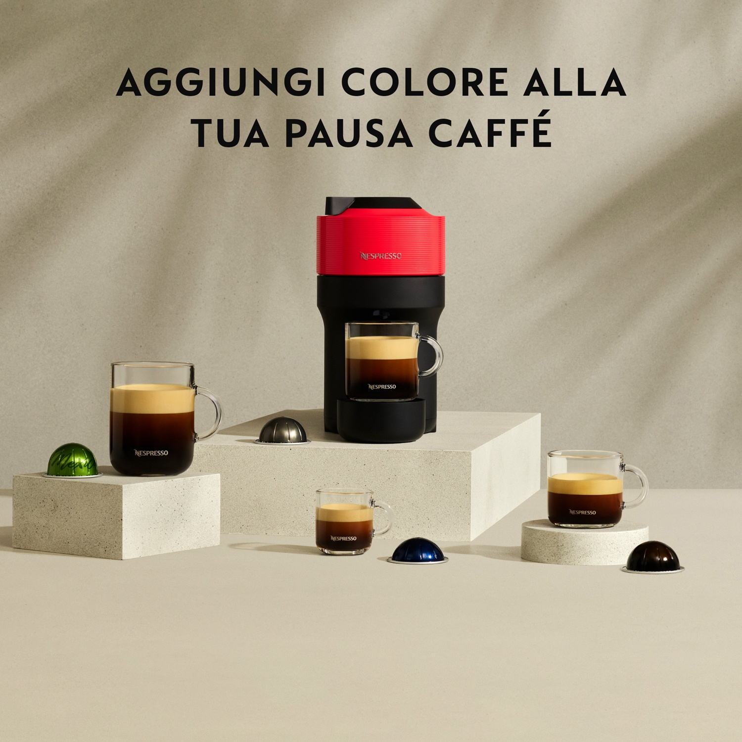 Una macchina da caffè Nespresso rossa con tre tazze di caffè e capsule.