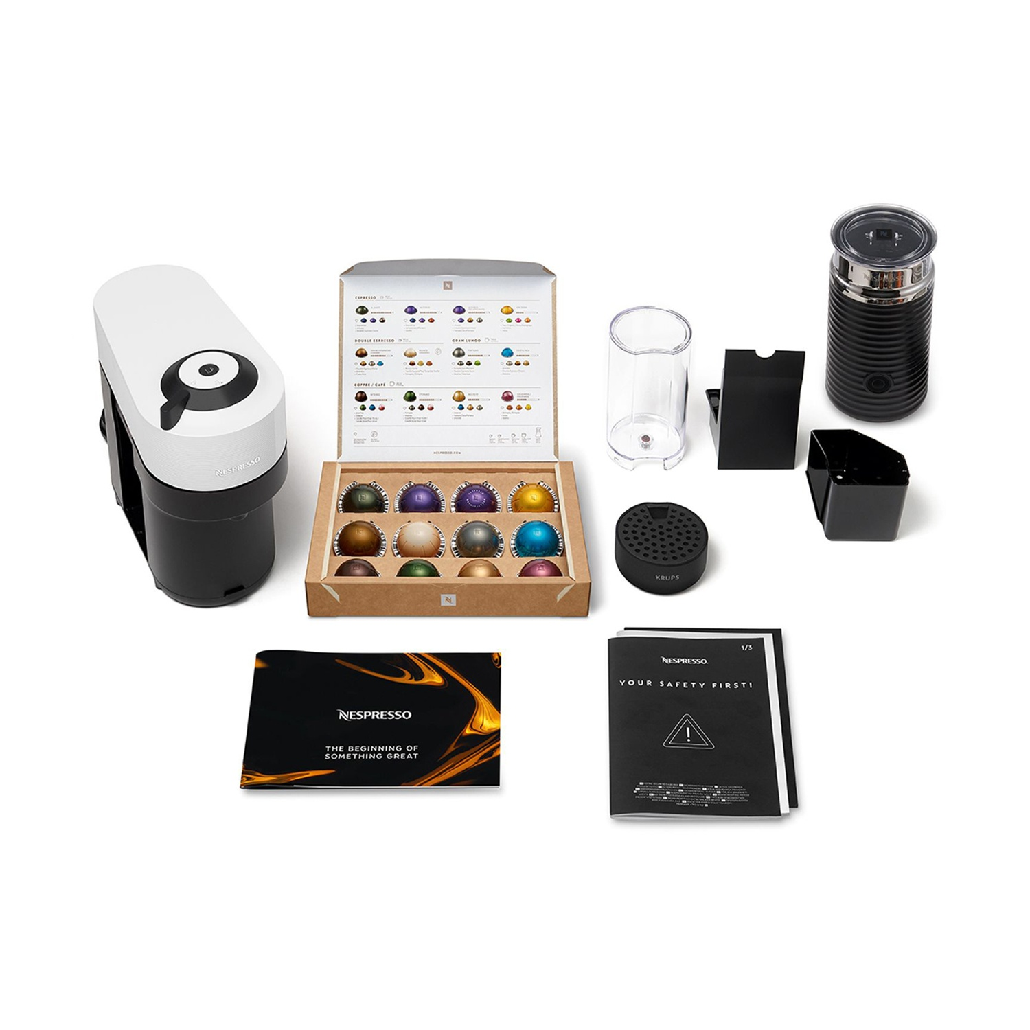 Macchina da caffè Nespresso con capsule, montalatte e accessori su sfondo bianco.