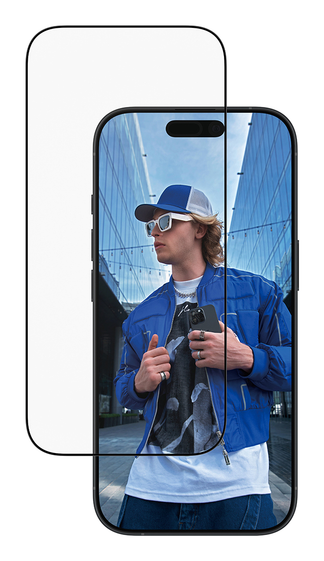 Ein Mann mit blauer Jacke und Kappe hält ein Smartphone, steht vor modernen Gebäuden.