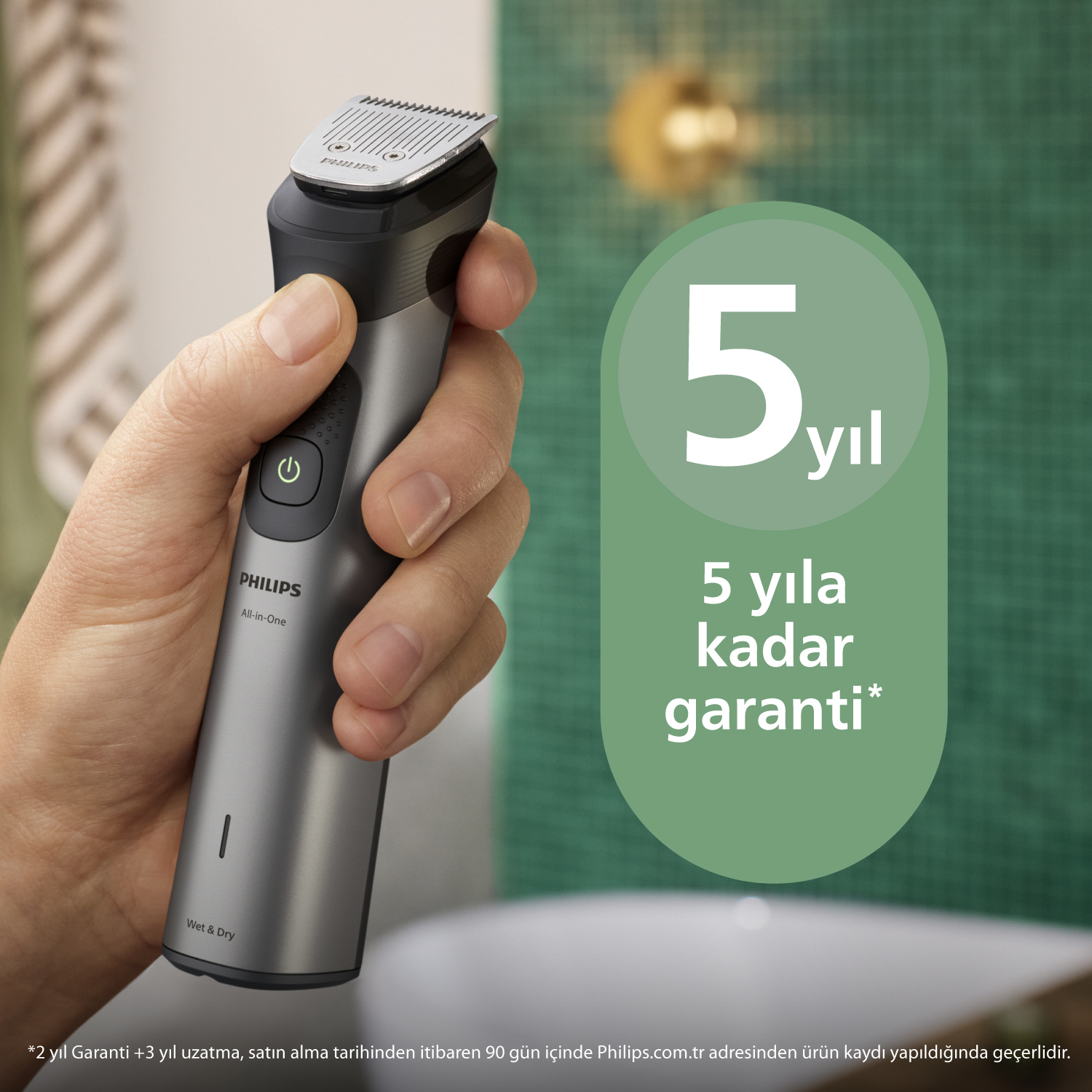 Elinde yeşil daireli gri Philips All-in-One tıraş makinesi tutuyor.