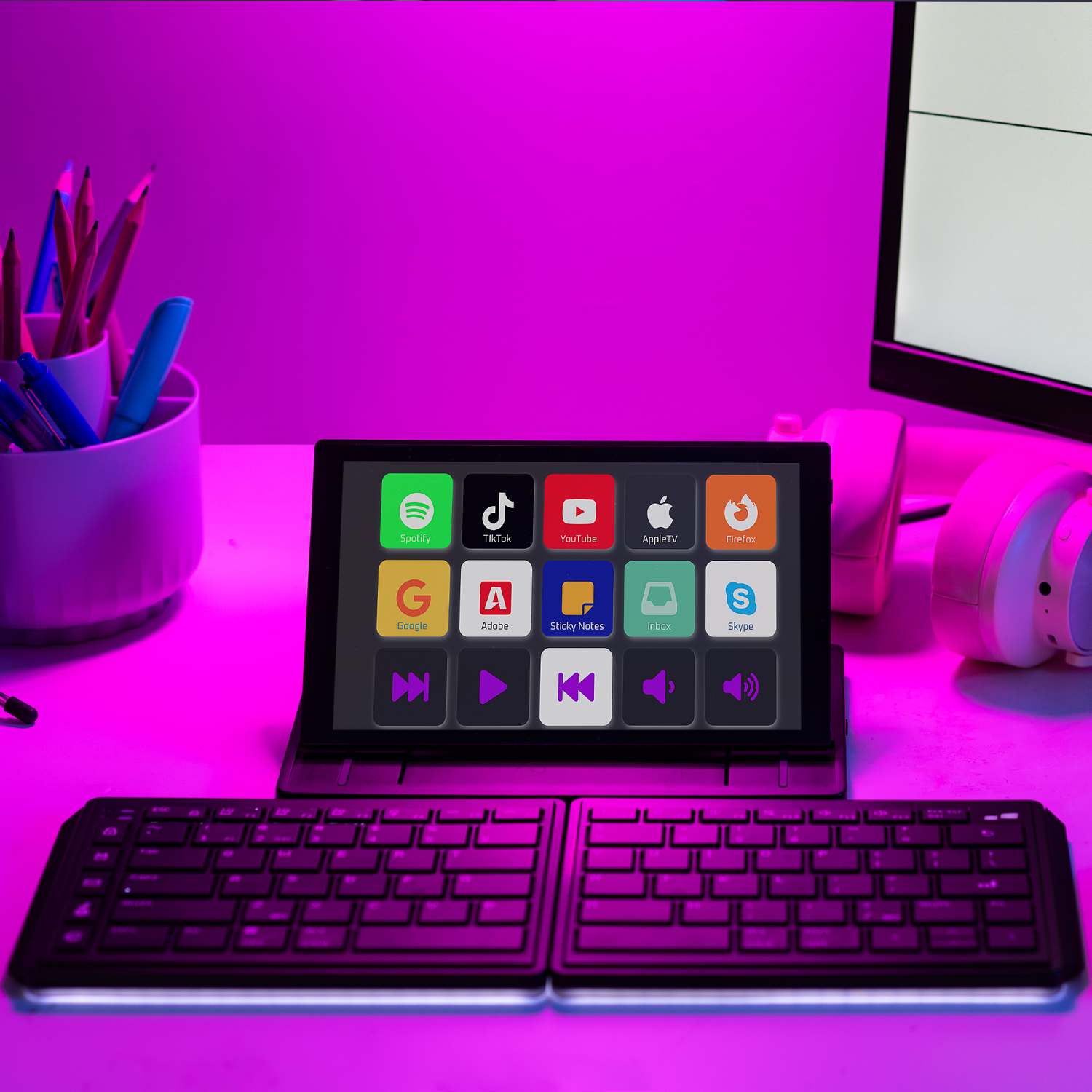 A tablet displaying app icons, with a keyboard in front, under purple light.