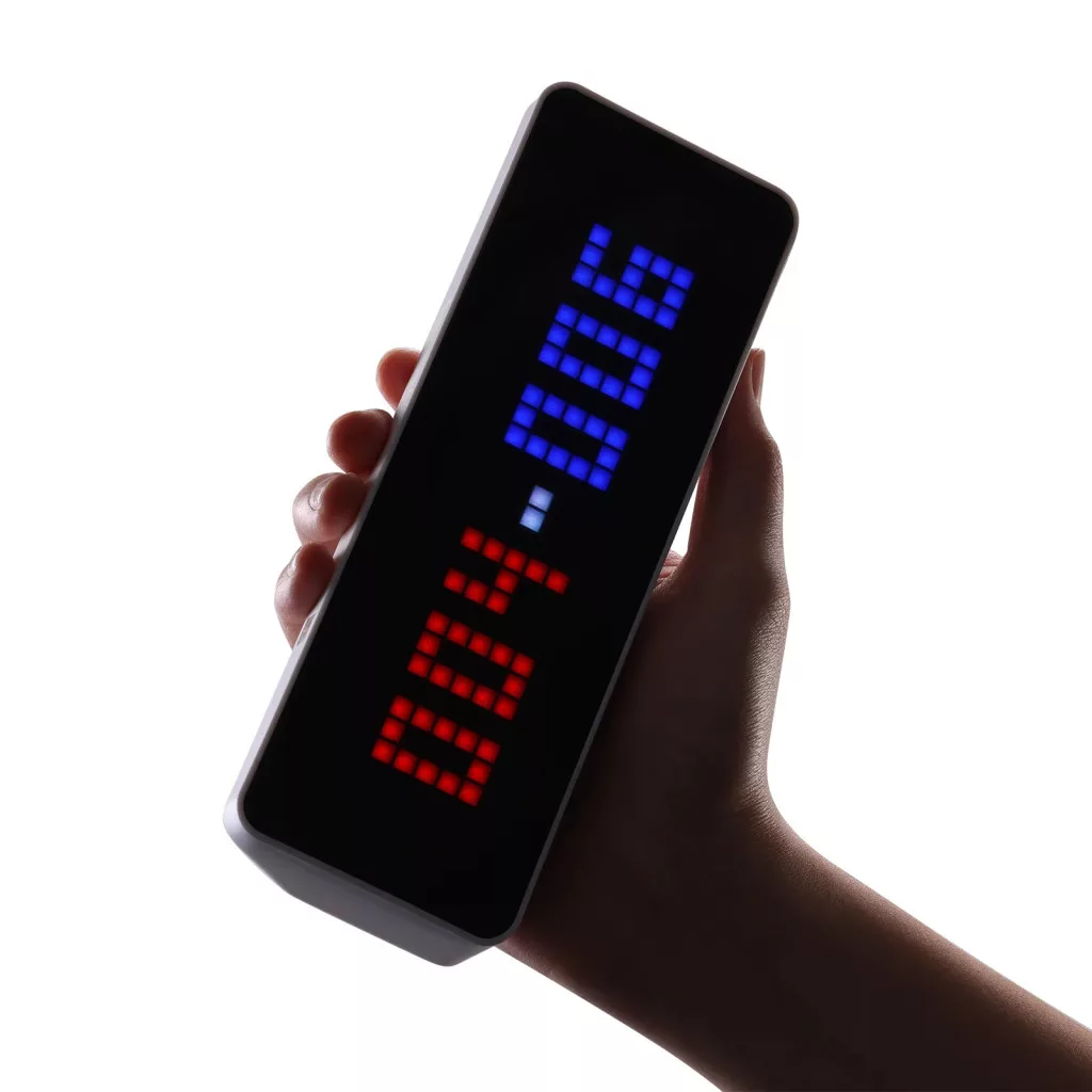 Egy kéz tart egy sötét, téglalap alakú eszközt világító LED kijelzővel.