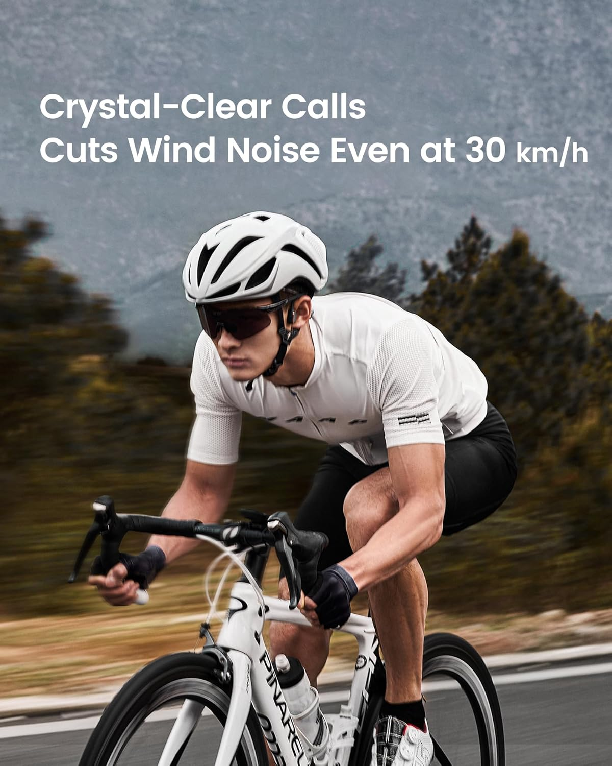 Un cycliste roule sur une route, casque et lunettes. Montagnes en arrière-plan.