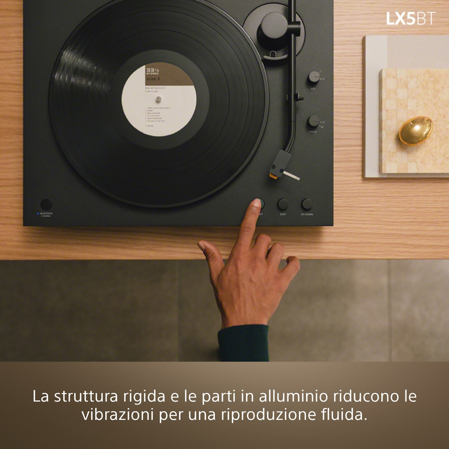 La mano di un uomo preme il pulsante di avvio di un giradischi con un disco in vinile.
