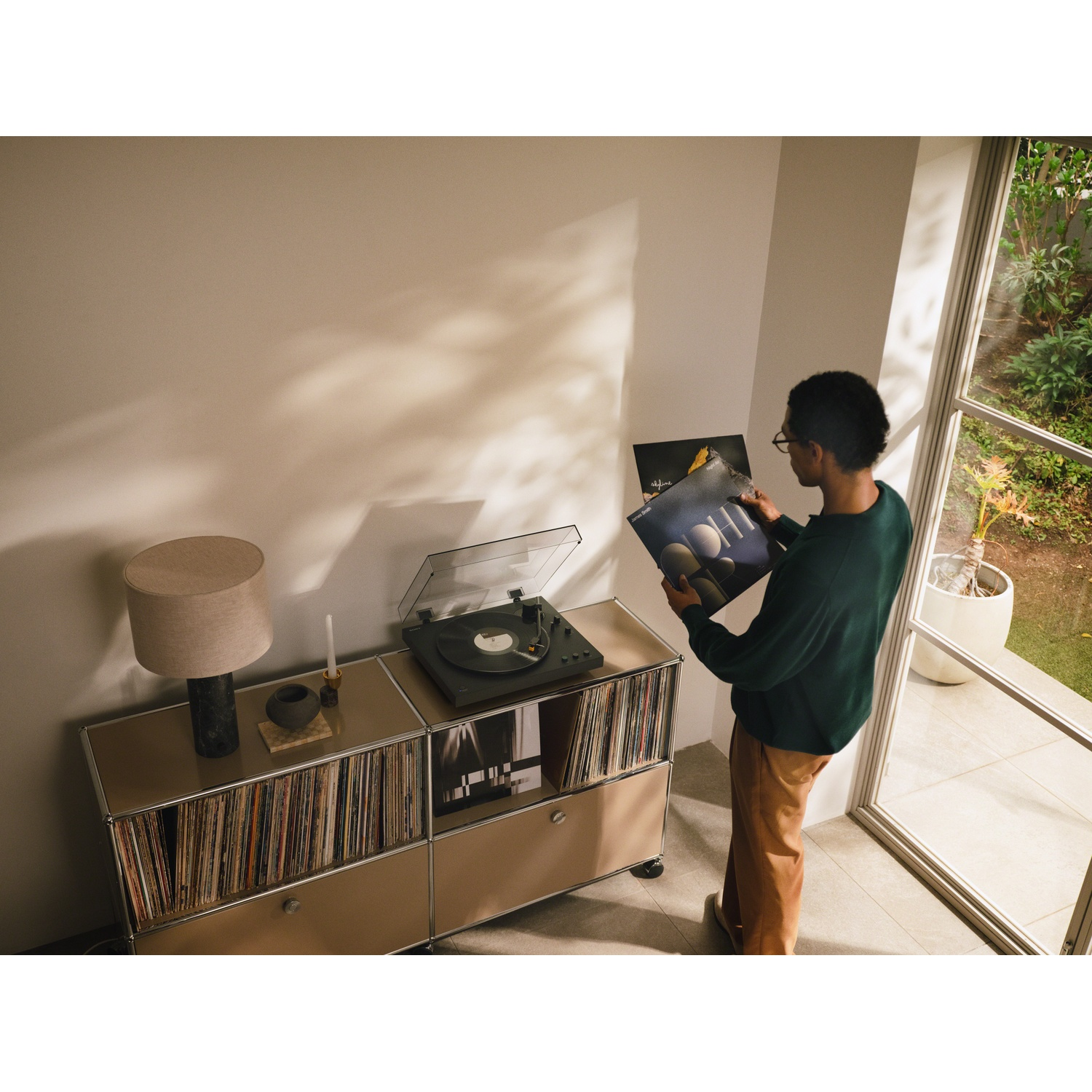 Man met vinylplaten in een zonnige woonkamer.
