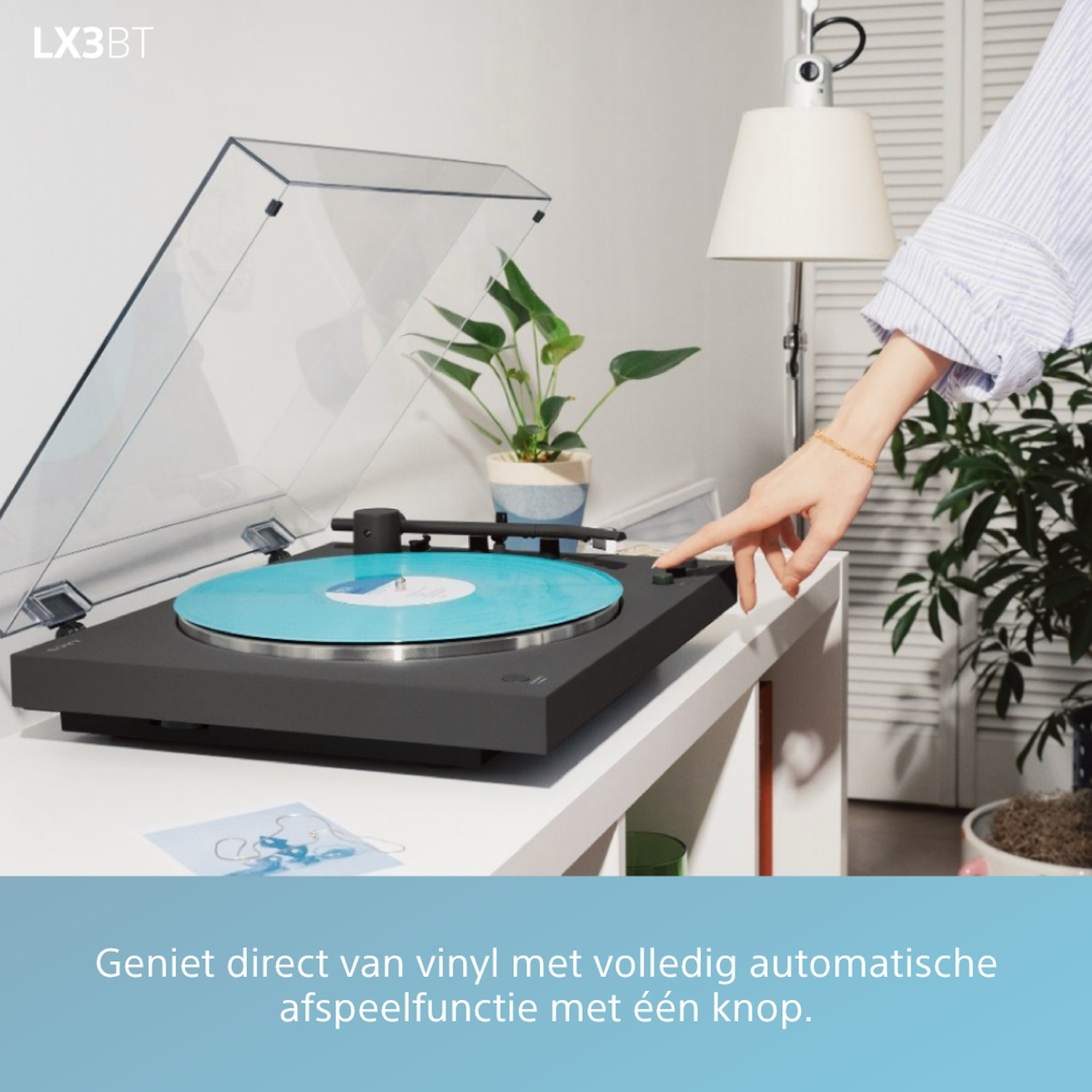 A turntable with a blue vinyl record and a hand pressing a button.