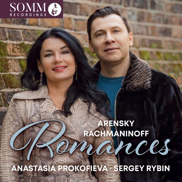 Ein Mann und eine Frau posieren vor einer Ziegelmauer. Titel: Romances.