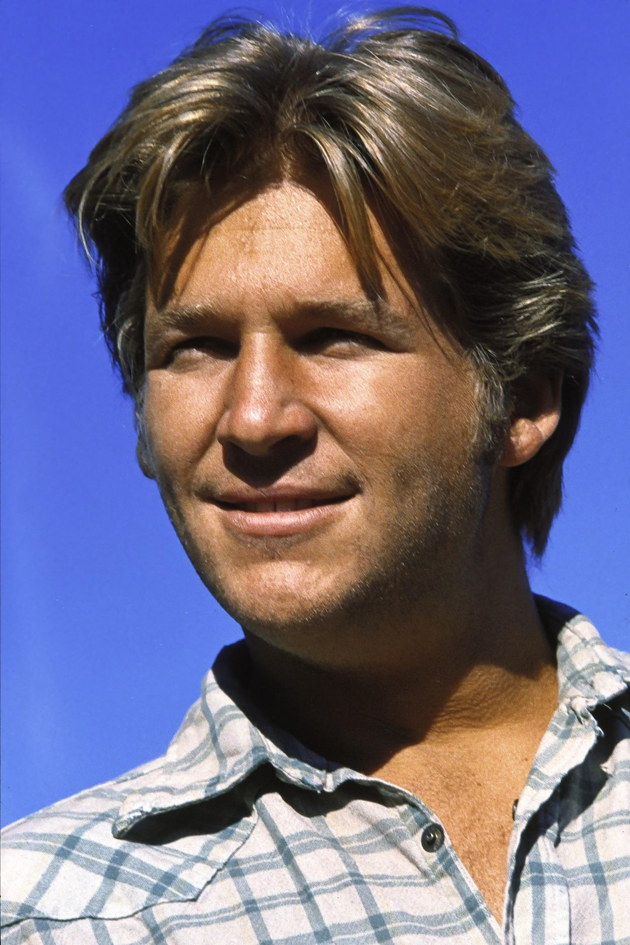 Nahaufnahme eines Mannes mit blonden Haaren, der ein kariertes Hemd vor blauem Himmel trägt.