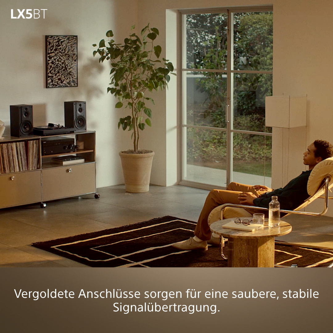 Mann entspannt sich im Sessel, Musik-Anlage im Hintergrund.