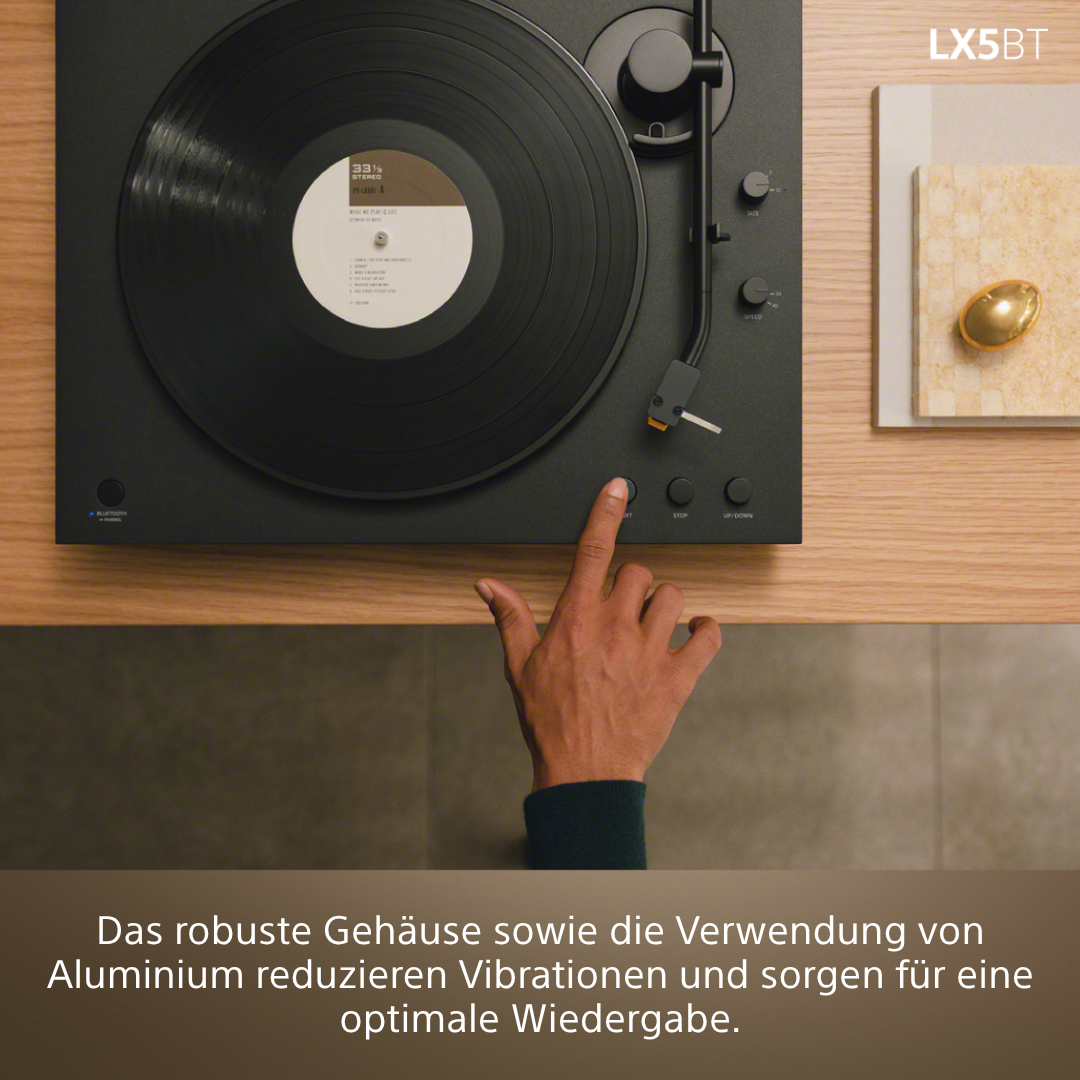 Ein Finger drückt den Startknopf eines Plattenspielers mit einer Vinylplatte.