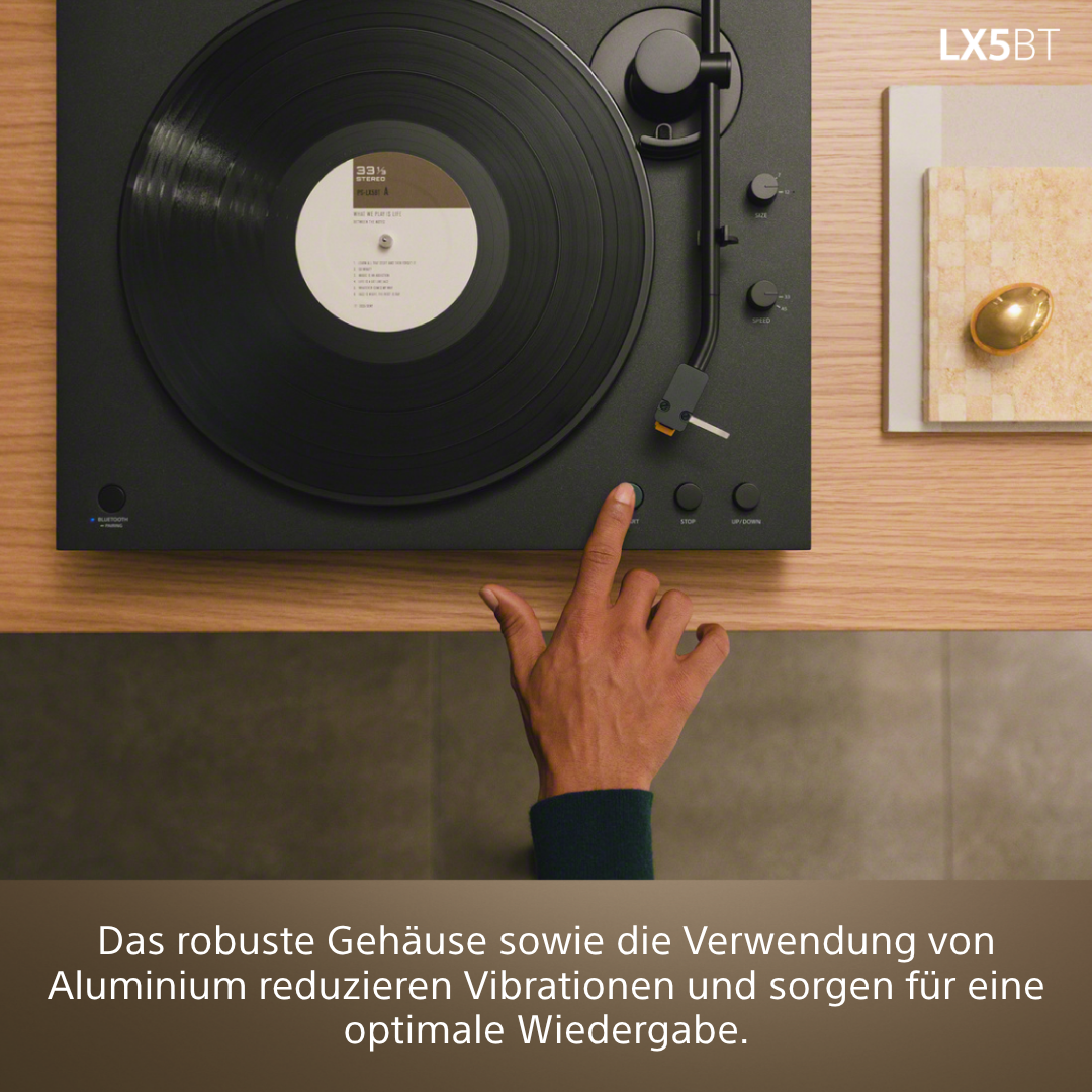Ein Finger drückt den Startknopf eines Plattenspielers mit schwarzer Schallplatte.