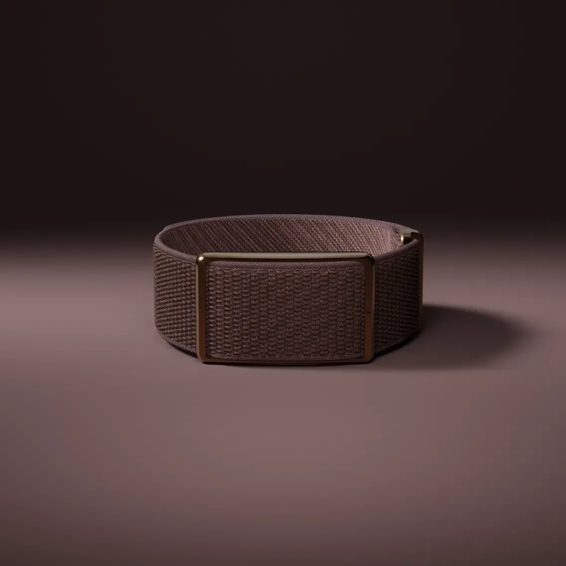 Una correa de tela marrón con hebilla metálica rectangular sobre superficie marrón.