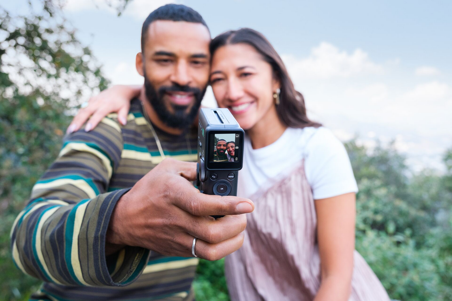 Un hombre y una mujer se toman una selfie con una cámara al aire libre.