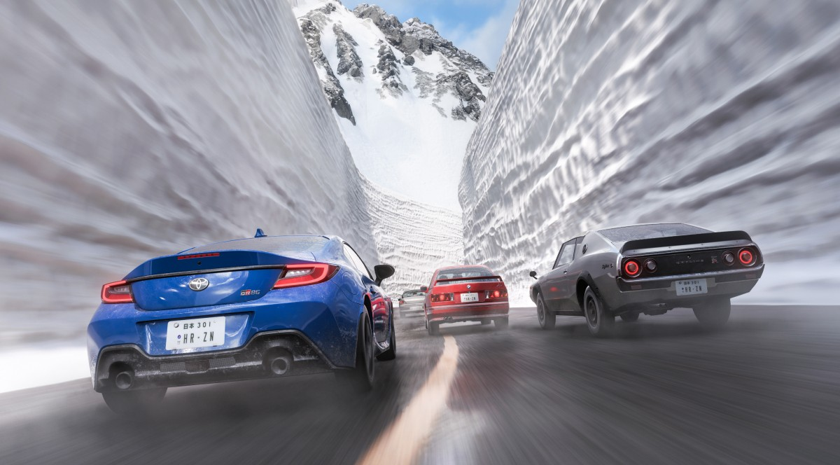 Autos fahren durch eine verschneite Schlucht mit Bergen im Hintergrund.