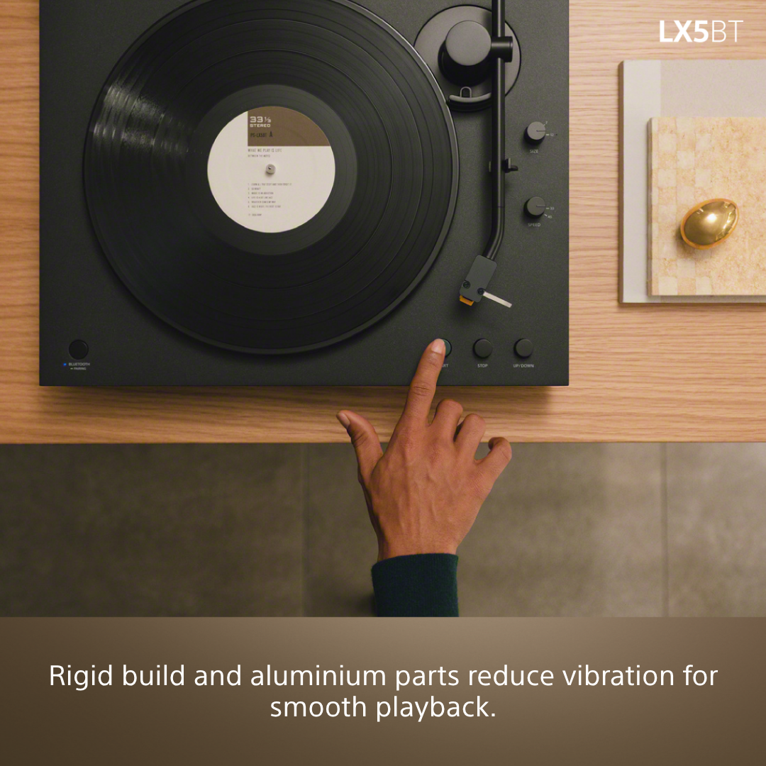 Un doigt appuie sur le bouton de démarrage d'une platine vinyle avec un disque.