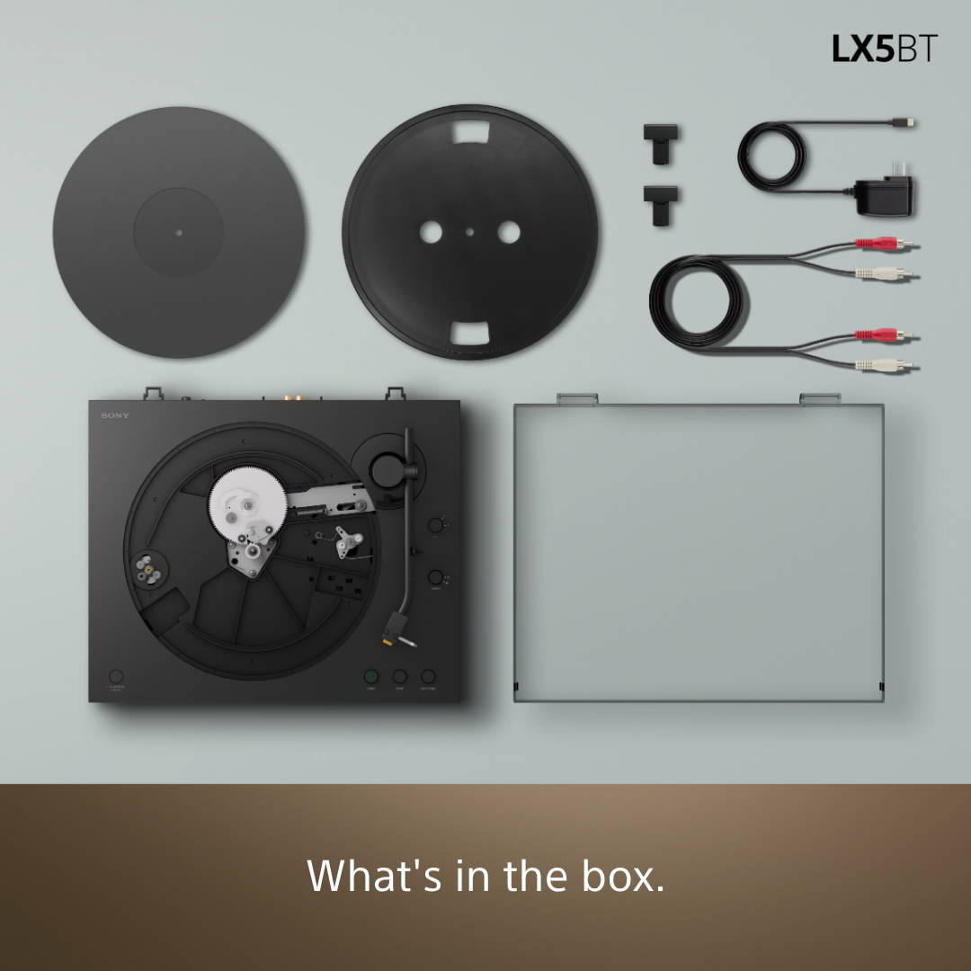 Platine vinyle noire avec accessoires : plateau, capot, câbles et adaptateur secteur.