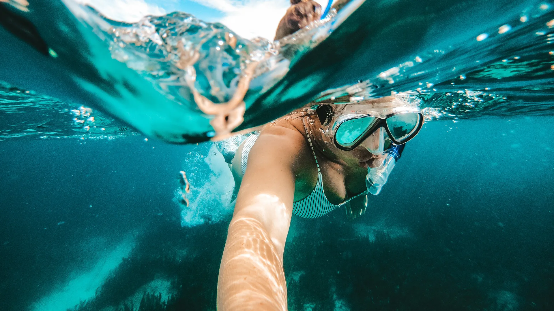 Eine Frau schnorchelt unter Wasser mit einer Taucherbrille und Schnorchel.
