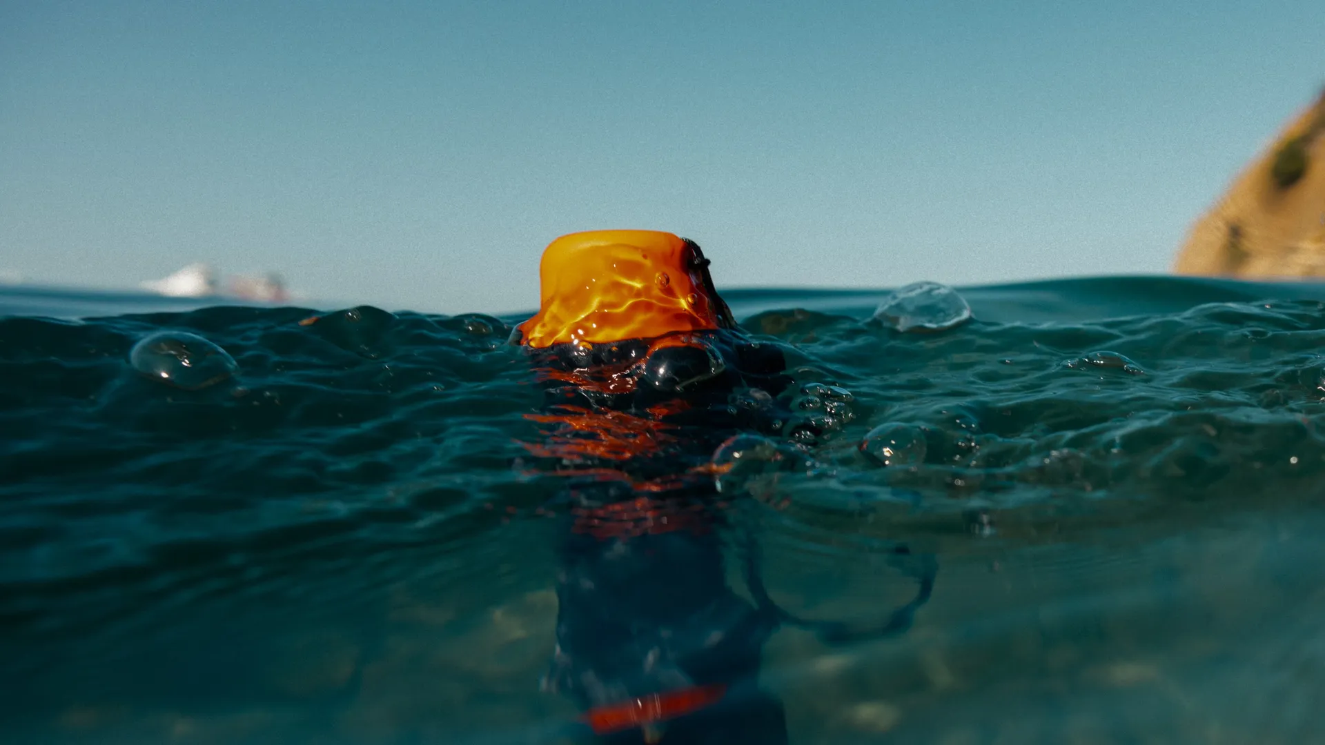 Ein orangefarbener Gegenstand ragt aus dem Wasser, Schiffe am Horizont.