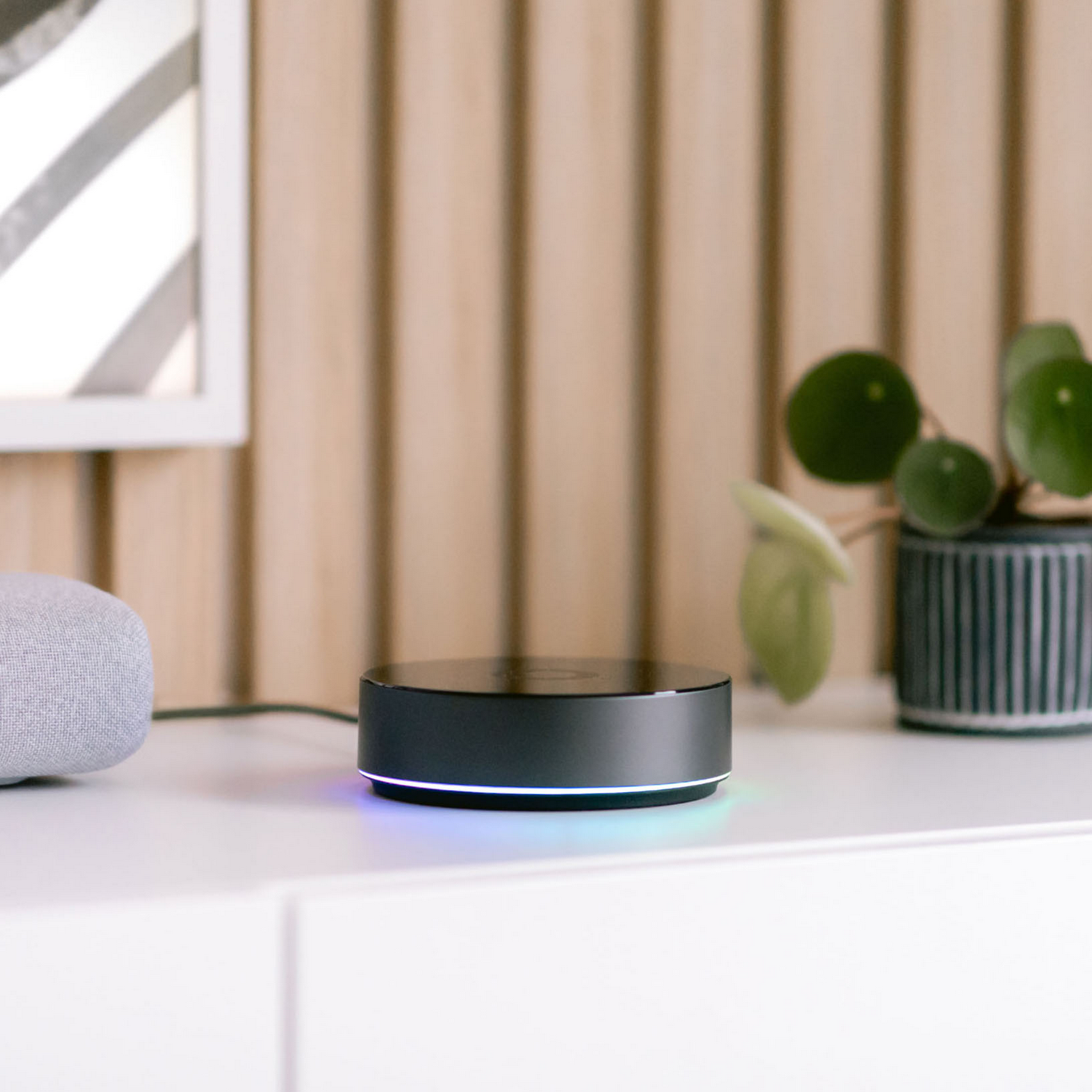 Un hub inteligente negro con anillo de luz junto a un altavoz gris.