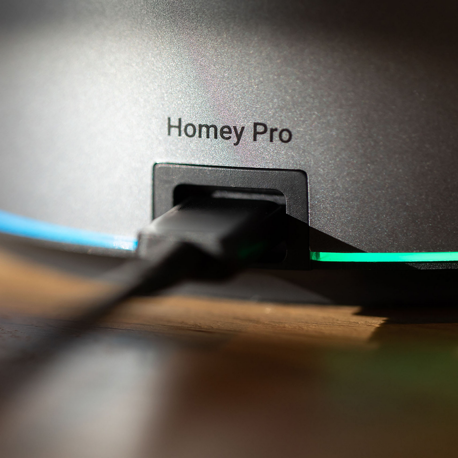 Un cable negro se enchufa en un dispositivo etiquetado "Homey Pro".